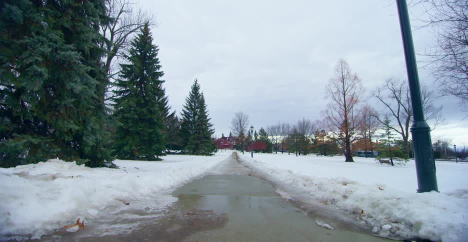 Snow covers ground bordering cleared road paralleling highway