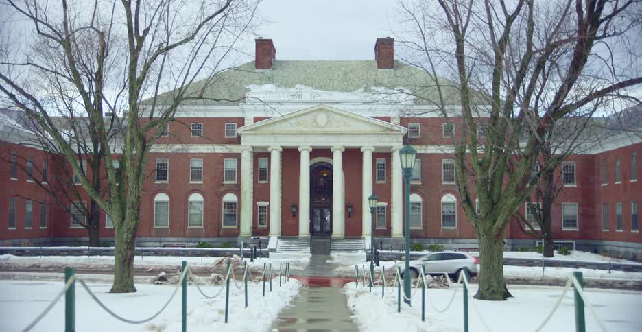 Cars driving past a building on a snowy day