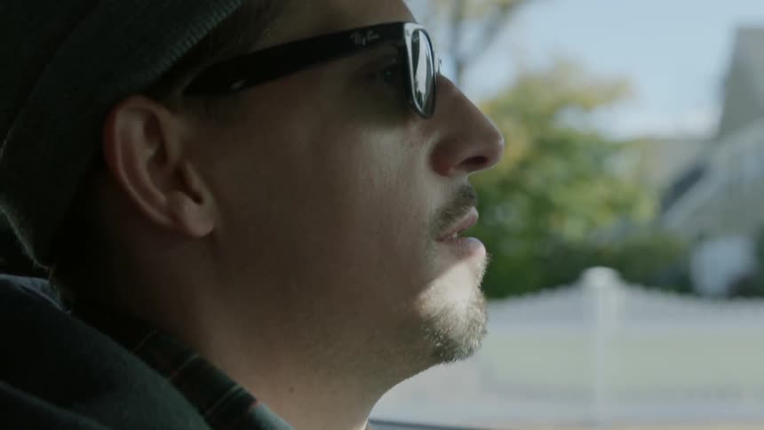 A man wearing sunglasses drives a car in the day time