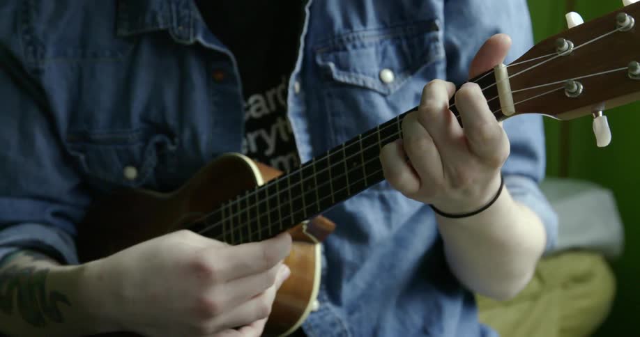 Close up of a woman playing a small guitar