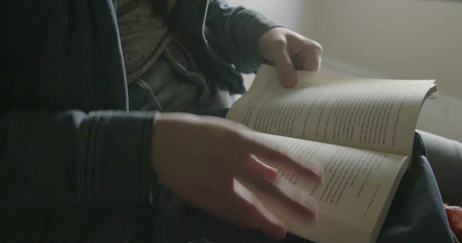 A person is seated flipping through a book