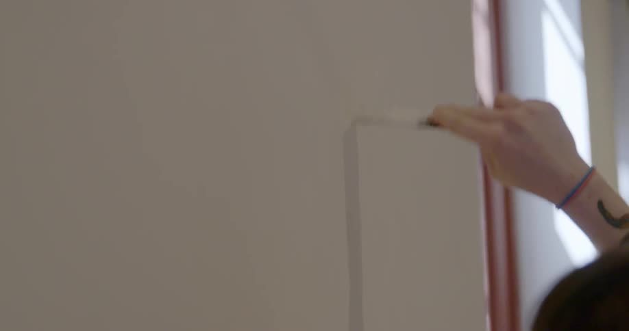 A woman patches a hole in a wall
