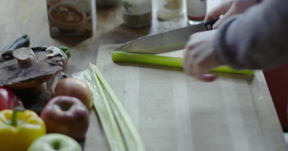A person is cutting celery on a board