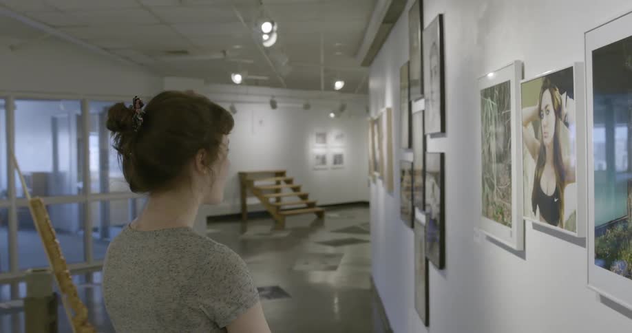A woman with brown hair looks at an art exhibit