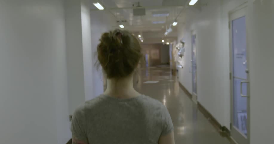 A woman is walking down a long hallway