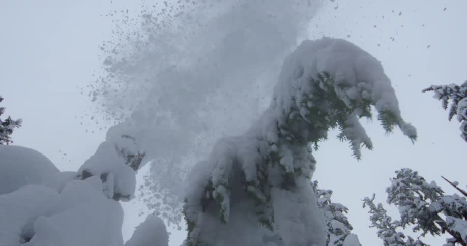 Snow falls on camera as a skier jumps high overhead