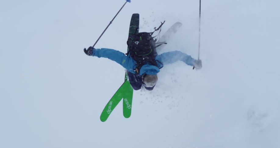 Skier does a 360 down the hill, filmed from a ski lift