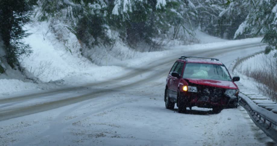 A smashed up vehicle at the side of a snowy road