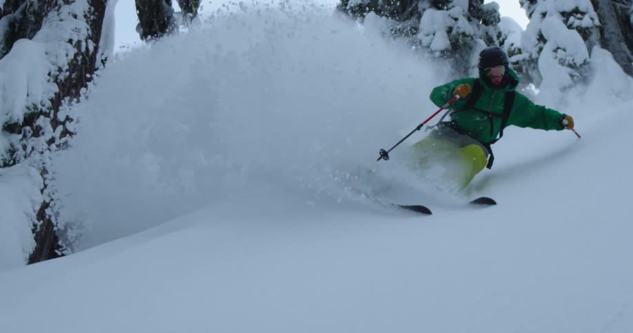 A skier turns and sprays a wall of powder