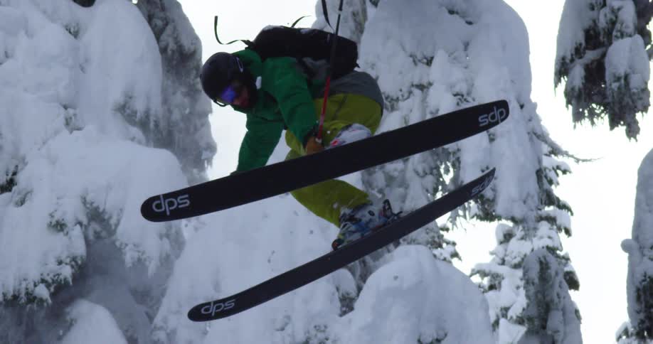 Skier jumps and does a 360 before landing and falling in deep powder