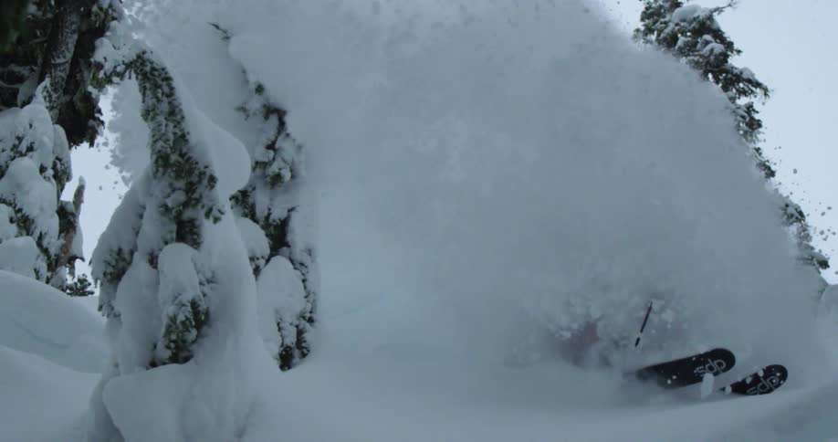 A skier slashes a huge spray of powder