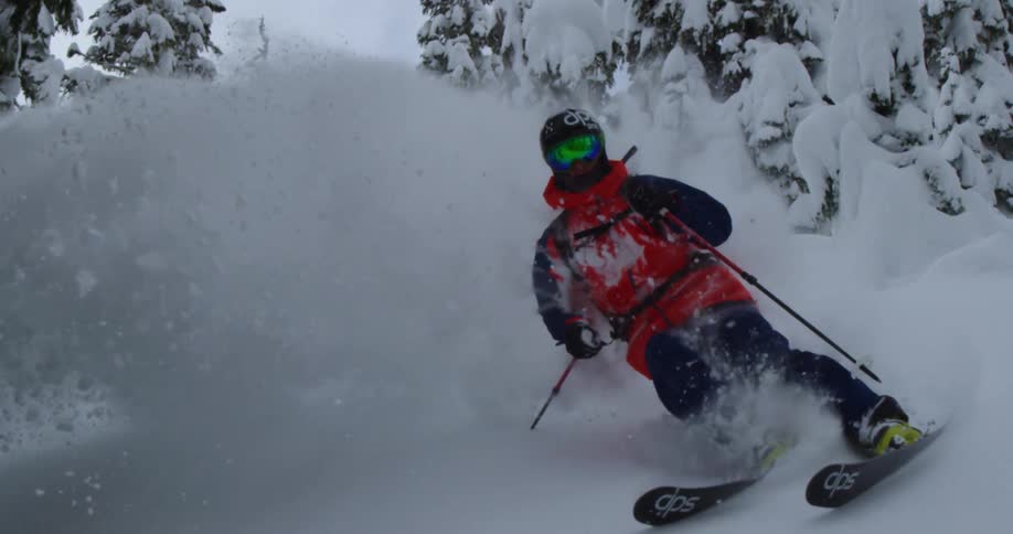 A skier in deep powder flies by the camera