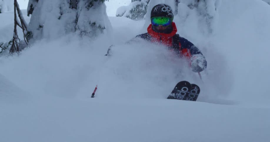 A man skis through deep powder, covered in snow