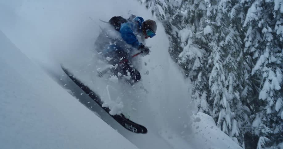 A skier turns through deep powder in the forest