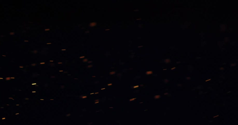 Snow particles fall in darkness
