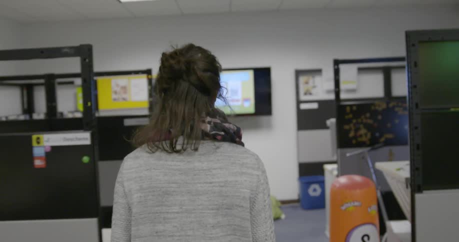 A woman walks past a number of cubicles in an office