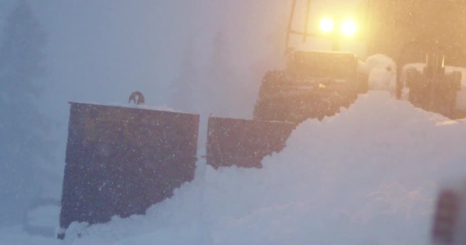 Snow plow operates in a heavy storm