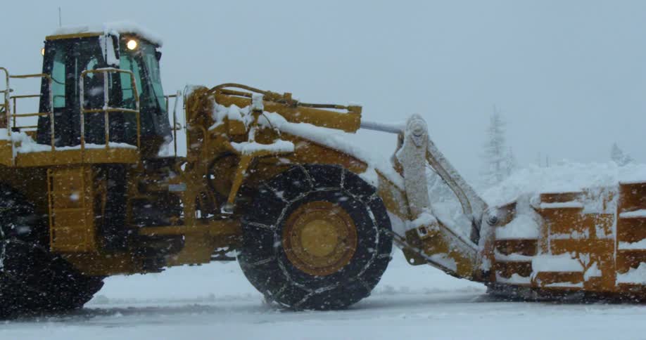 A snow plow clears a road in heavy snow