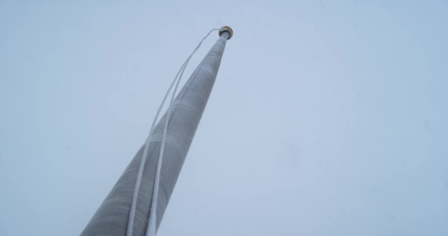 Snow falls around a flagpole