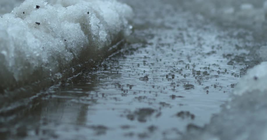 Rain falls in a slushy puddle
