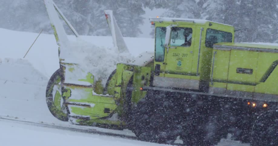 A person driving a snow plow in a blizzard