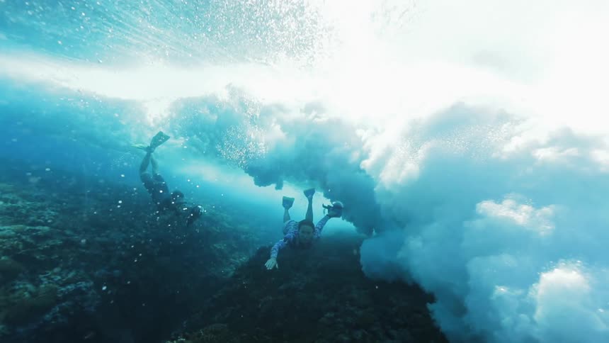 Underwater footage of divers filming waves over the corals in the blue ocean waters