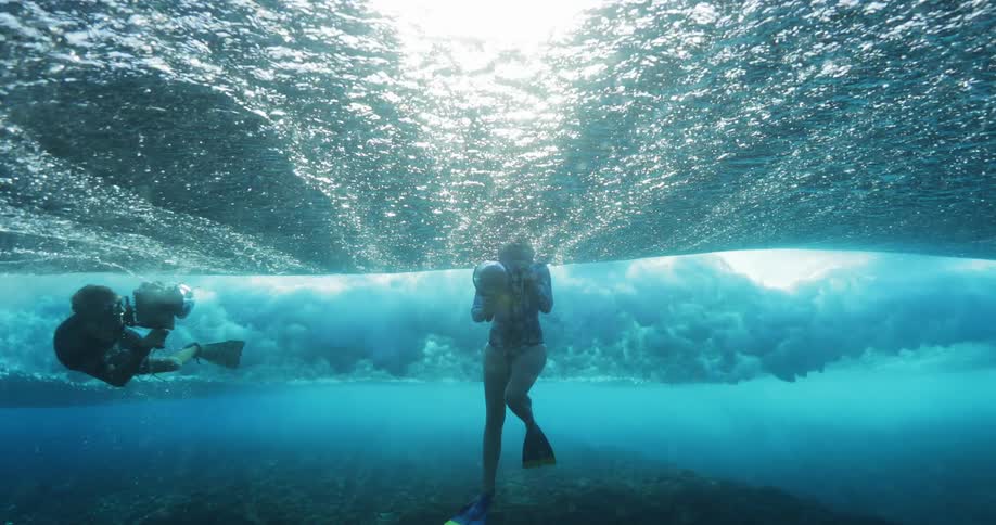 Divers filming underwater footage on the shallow blue ocean waters
