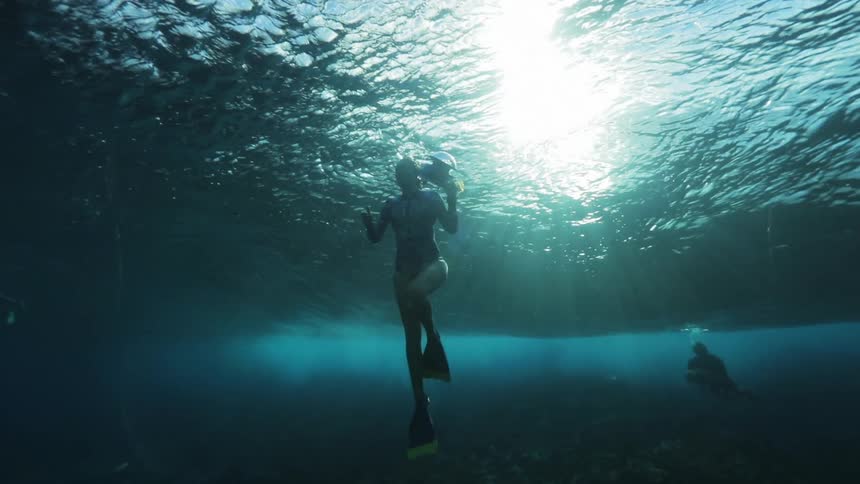 A woman takes pictures as she swims under water with a man