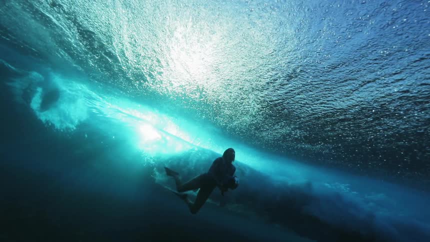 A huge wave rolls over a swimmer with a camera underwater