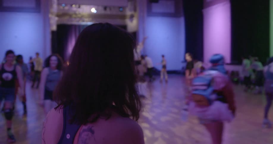 A woman with dark hair watches others skate