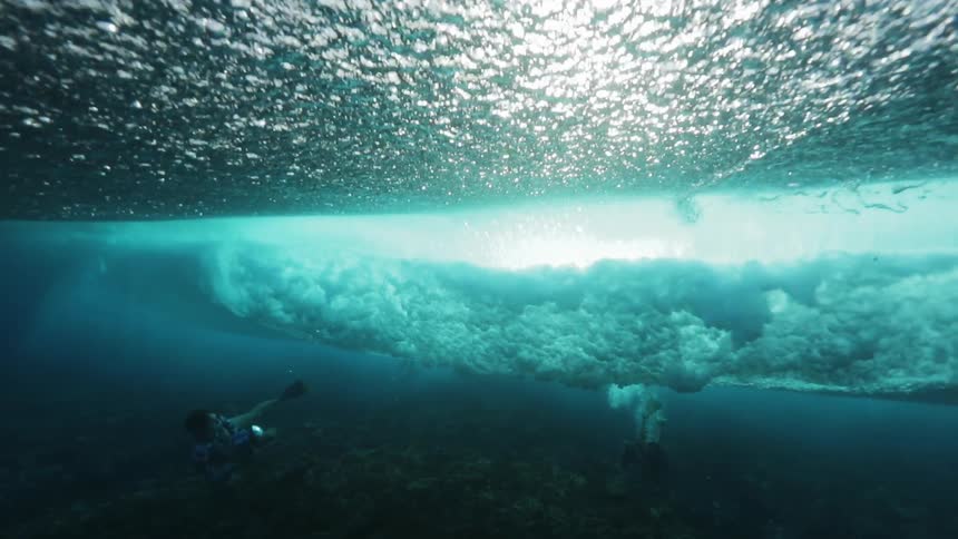 A woman in the water filming turbulent waves in clear waters