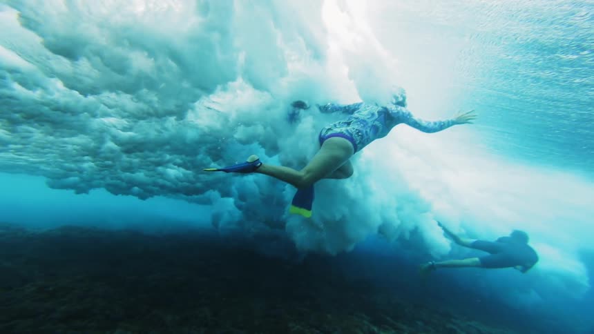 Underwater footage of swimmers being swept by a wave on the shallow ocean waters