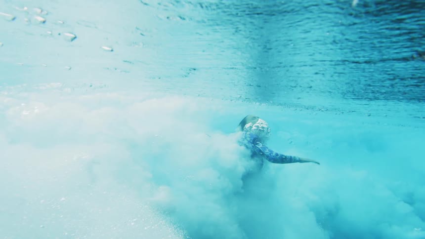 A woman escapes heavy ocean waves to breath at the surface