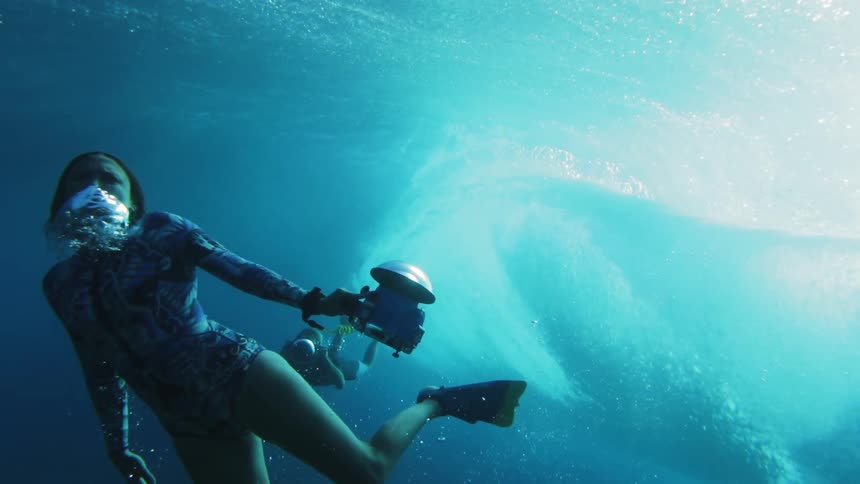 A woman swims as a wave rolls over her head