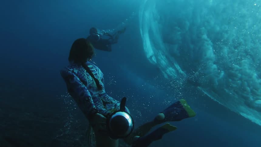 Underwater photographers swim under waves