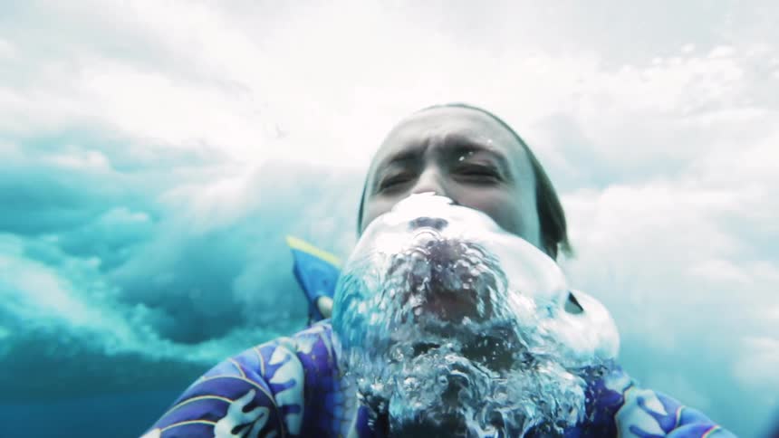 Woman waits for wave to crash overhead before surfacing as she blows out bubbles