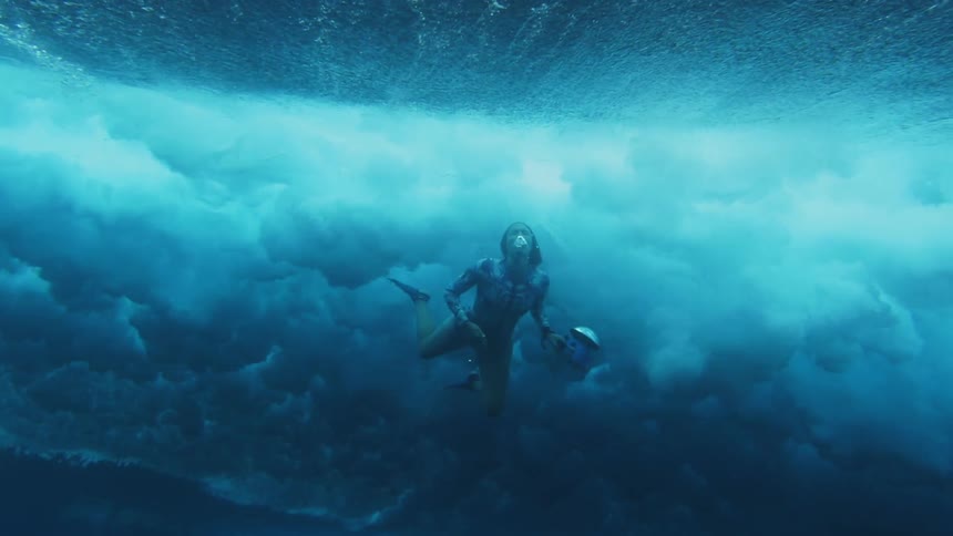 A woman swimming underwater as waves pass above her