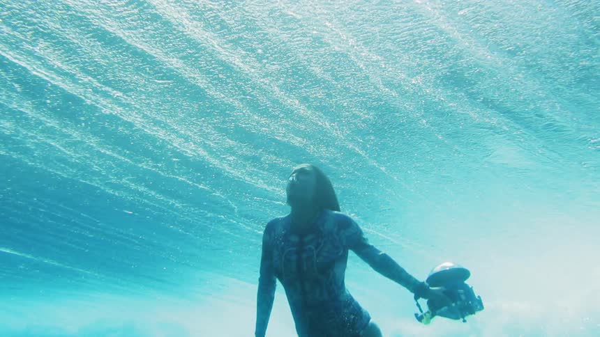A diver wearing a patterned suit swims up to the surface of the water