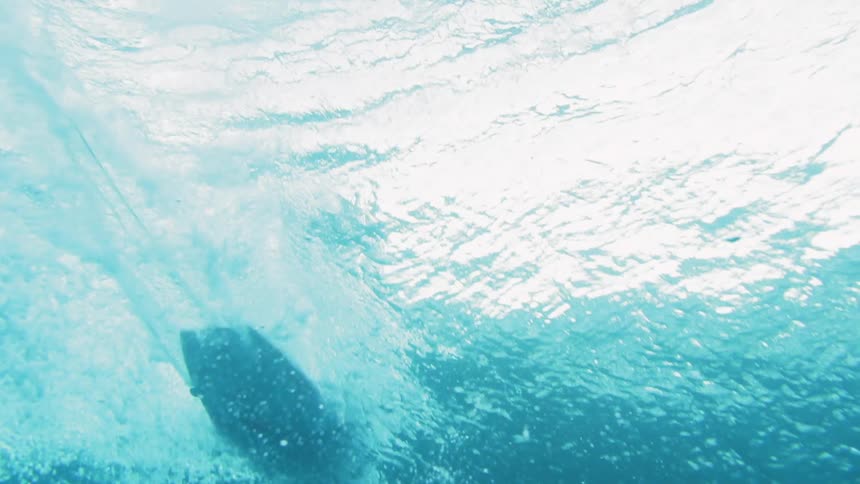 Underwater as a surfboard rides by overhead