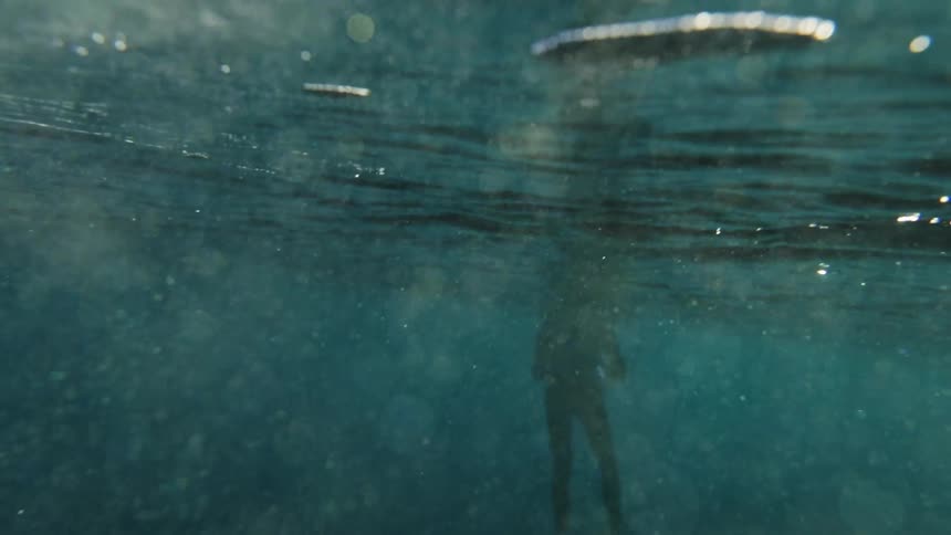 Glimmering bubbles underwater and a person beyond