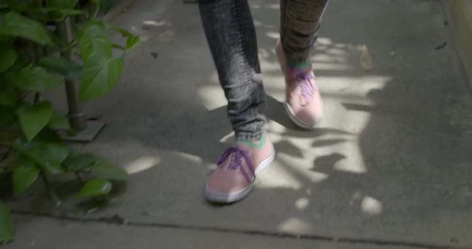 Person wearing pink tennis shoes walks down path