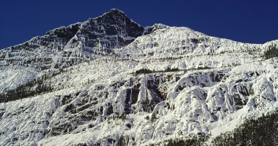 Peaks of a mountain covered in snow under a clear blue sky