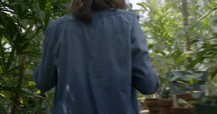 A woman walks through a greenhouse