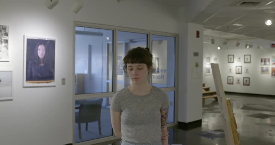 A woman is standing in a art house with her arms behind her back