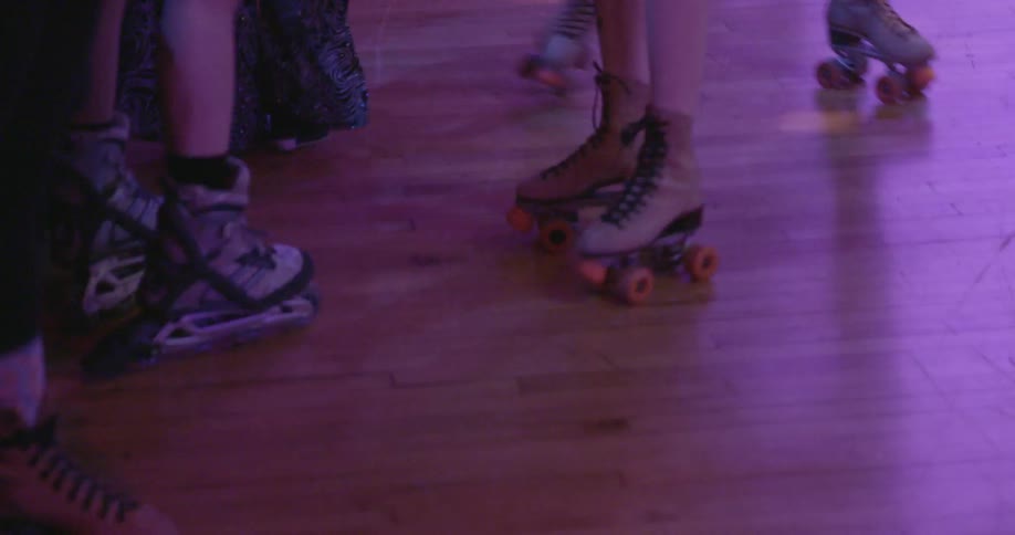 People are on a roller rink dancing and skating