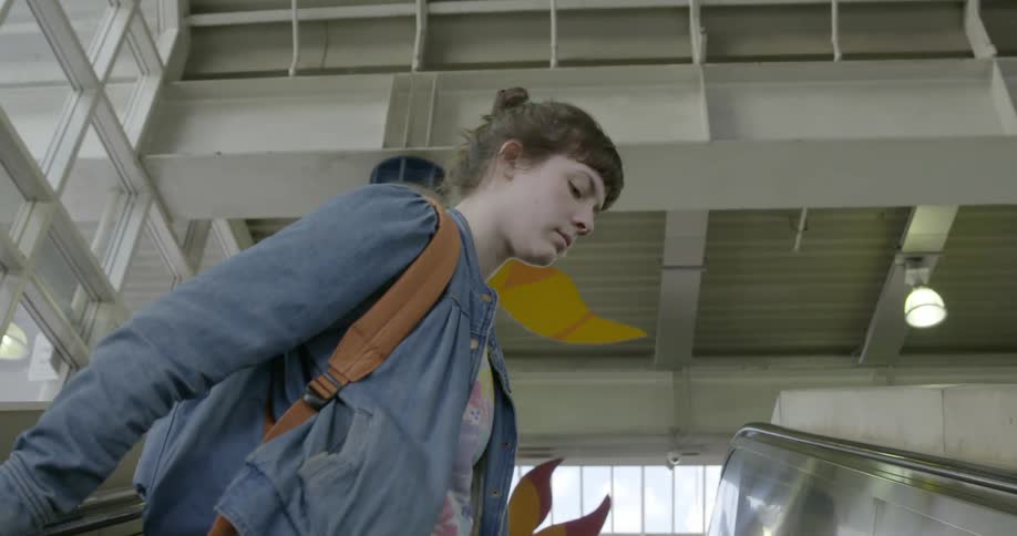 A young woman looks around as she rides up an escalator