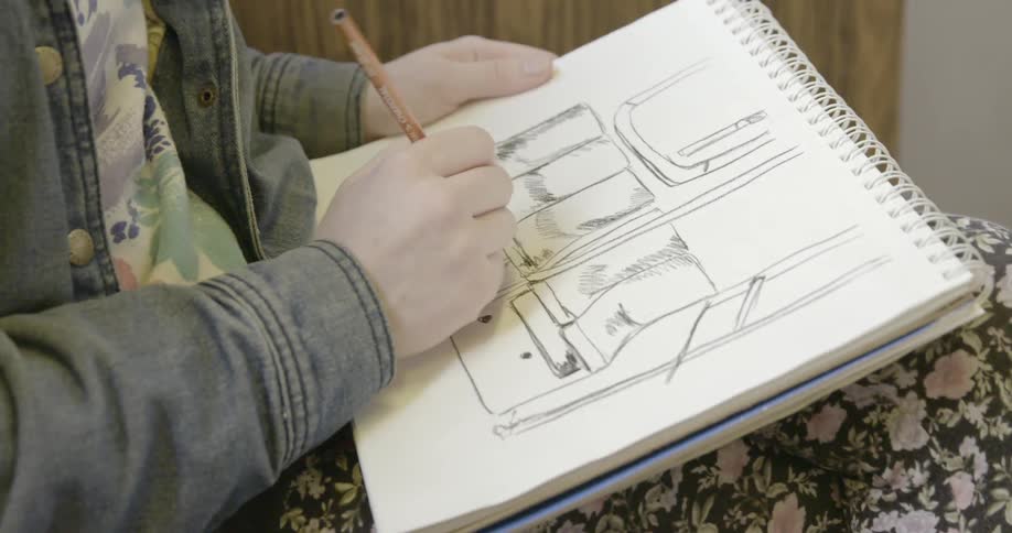 A person is seating drawing in a pad