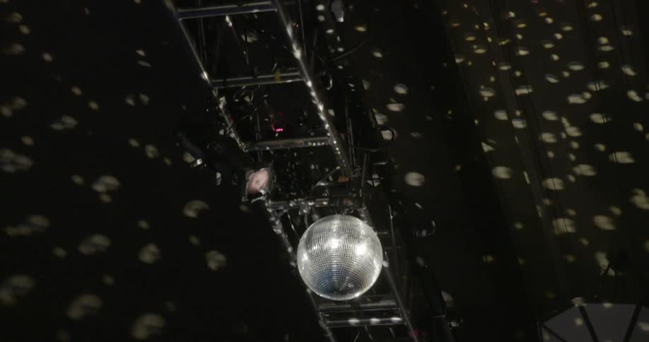 A disco ball hanging from a rafter is spinning around