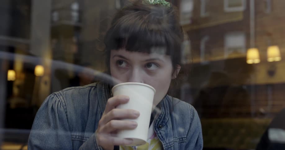 Woman sips from a cup while sitting in a restaurant