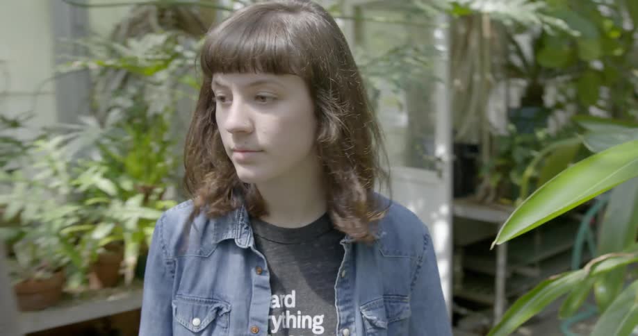A woman is walking through a greenhouse looking around